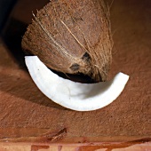 Kokosnußspalte, im Hintergrund eine halbierte Kokosnuß