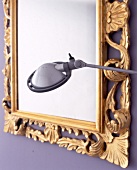 Detail: schnörkeliger Spiegel mit Goldrahmen