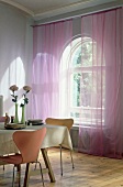 Room with pink curtains in front of old styled window