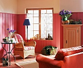 Wohnzimmer im Rot-Ton: Holzverkleidete Wände, Korbstuhl,Fliesen