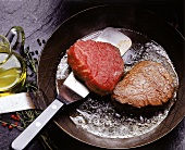 Zwei Steaks werden in einer Pfanne gebraten
