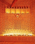 Wand mit indischer Ton-Stukkatur, von vielen Kerzen beleuchtet