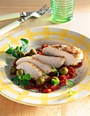 Chicken breast with tomato olive sauce on plate