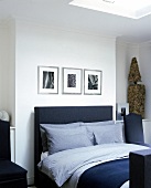 Schlafzimmer: dunkles Bett, darüber hängen Pflanzenfotos