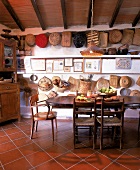 Eßplatz in der antik eingerichteten Küche, an der Wand hängen Körbe