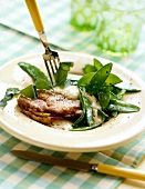 Sage-schnitzel and sweet peas with fork on plate