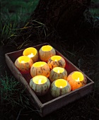 Lit candles in hollowed-out musk melons in wooden tray