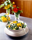 Bowl of green salad with asparagus, sugar snap peas, and flower