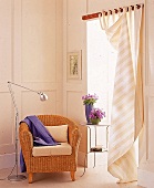 Korbsessel mit lila Decke steht in der Leseecke(beige/weißer Vorhang)