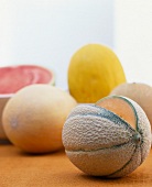 Galia-Melone,Fruchtfleisch sichtbar, im Hintergrund mehrere Melonen