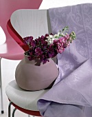 Zartlila Stoff hängt über zwei aufeinandergestapelten Stühlen(Vase)