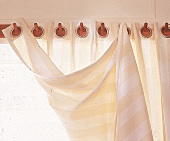 Hakenleiste aus Holz mit angehängtem hell gestreiften Vorhang