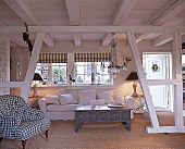 Wohnzimmer mit weißen Holzbalken, weißem Sofa, Sisalteppichboden