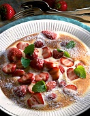 Close-up of strawberry gratin garnished with mint leaves and icing sugar