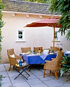 Covered patio table with wicker armchairs and parasol in garden