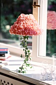 Tischlampe dekoriert mit rosa Rosen- blättern und Efeuranke