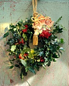 Close-up of Christmas holly wreath with angel and gold cord on wall