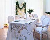 Festive table laid with white crockery, decoration and tablecloth with narrow overprint