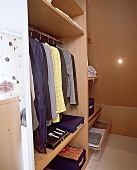 Begehbarer Kleiderschrank aus hellem Buchenholz mit Kleidung