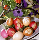 kunstvoll mit Blüten verzierte und gefärbte Ostereier in einer Schale