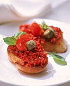 Crostini mit Tomatenpaste und Basilikumblätter.