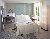 Elegant kühles Schlafzimmer mit Arbeitsplatz hinter Glasschiebetür