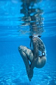 Side view of woman performing aqua aerobics underwater for toning her butts and legs