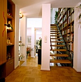 Bücherwand aus Holz hinter Holz- treppe - damit gut erreichbar