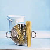 Ein Kochtopf, ein Siebeinsatz und rohe Spaghetti   (Freisteller)