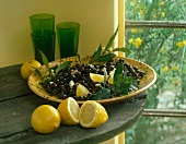 Schwarze Oliven in einer Schale mit Zitronenspalten