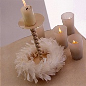Kerzenständer mit einem  weißen Federkranz,daneben kl. Windlichter