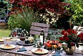 Gedeckter Tisch mit roten Rosen,Obst Rotwein und Spaghettigericht.