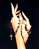 Close-up of woman's hand wearing colourful nail polish holding rosary