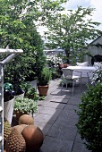 Dachterrasse mit großen Bodenplatten und Bäumen u. Sträuchern in Kübeln