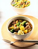 Bowl of vegetable soup with meatballs on wooden board