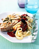 Close-up of tagliatelle with tomato sauce, tuna, olives, almonds and rosemary on plate