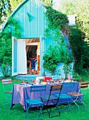 Bunt gedeckte Tafel im Garten, blaue Tischdecke, Haus im Hintergrund