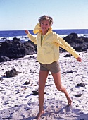 Frau läuft barfuß am Strand, gelbe Jacke, Shorts