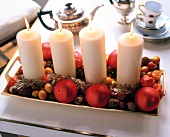 Four white lit candles with fir branches on tray