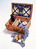 Geöffneter Picknickkorb mit Besteck, Geschirr und eine Auswahl franz Käse