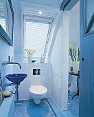 Blue tiled bathroom with commode and wash basin