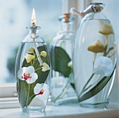 Glass jar of oil lamp with silk orchid