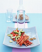 Scampi-Spieße mit Avocado-Salat auf einer eckigen, blauen Schale