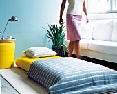 Woman walking beside guest bed and white sofa