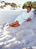 Frau liegt in den Dünen im Sand trägt ein Shirt in weiß