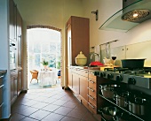 View of open kitchen with sleek maple furniture and stainless steel utensils