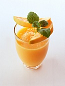 Low-fat cocktail of mango orange juice with slices of mango and mint toppings