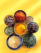 Various bowls with spices on yellow background