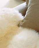 Detail: graues Leinensofa mit passendem Kissen + weißem Lammfell
