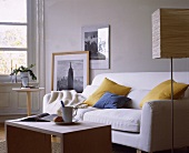 Weißes Sofa+blau-gelbe Kissen,Holz tisch schlicht, Papierstehlampe